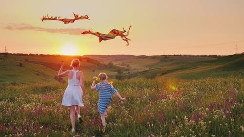 Mom and Daughter Together Launch Kites. In a Picturesque Place at Sunset. Happy Family Concept