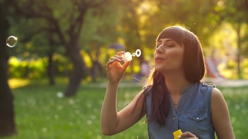 Woman Blowing Bubbles in a Sunny Park