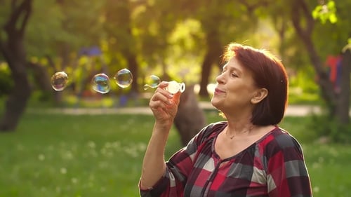 Woman Enjoys Blowing Bubbles in Golden Sunlight