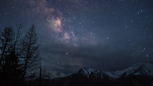Die Milchstraßengalaxie liegt in einer klaren Nacht über schneebedeckten Bergen