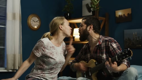 Couple Singing and Playing Guitar in Bedroom