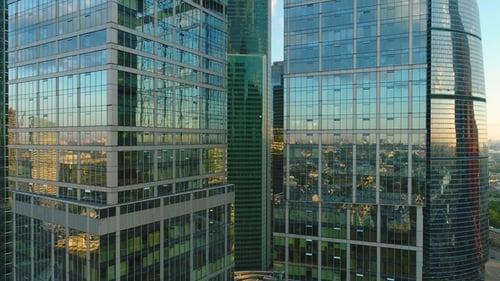 Flying Up Between Two Modern Tall Skyscrapers with Offices and Apartments at Sunrise. Aerial View