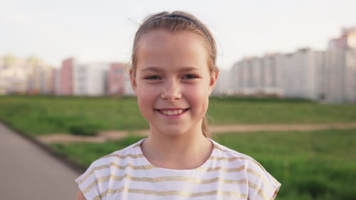 Smiling Girl Posing in Front of a Park