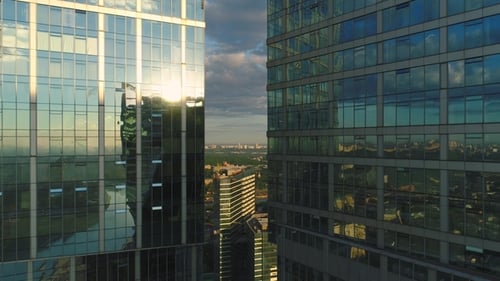 Flying Backward Between Two Modern Tall Skyscrapers at Sunrise