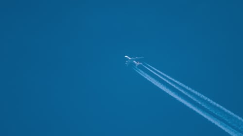 Jet Plane Flying Across Blue Sky, Leaving Trails