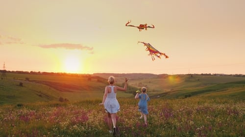 Woman and Girl Fly Kites in Sunset Field