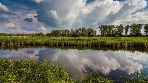 Fluss im Frühling an einem hellen sonnigen Tag Blauer Himmel mit weißen Wolken