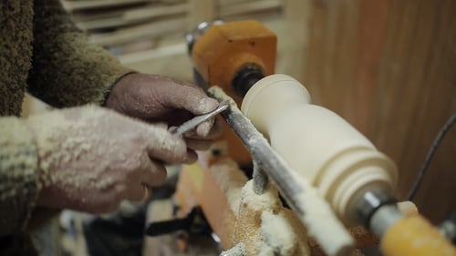 Woodworker Shaping Wood with Lathe and Metal Tool