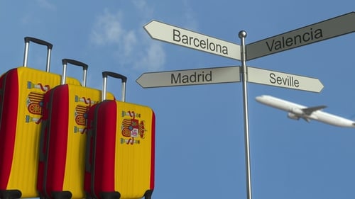 Spain Travel Concept with Suitcases, Destination Sign, and Flying Airplane