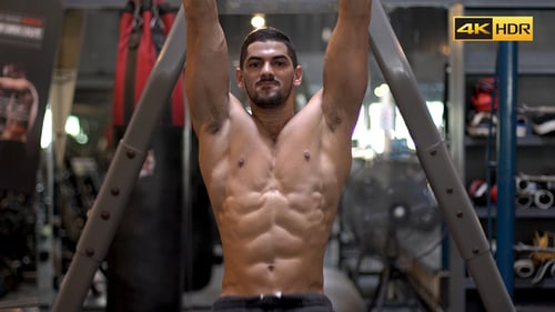 Muscular Man Doing Leg Raises at Gym