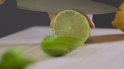 Lime Sliced on Wooden Board with Sharp Knife