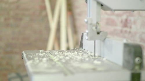 A Man in a Carpentry Workshop Wearing Protective Glasses Cleans the Board