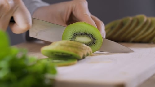Slicing a Kiwi on a Wooden Board