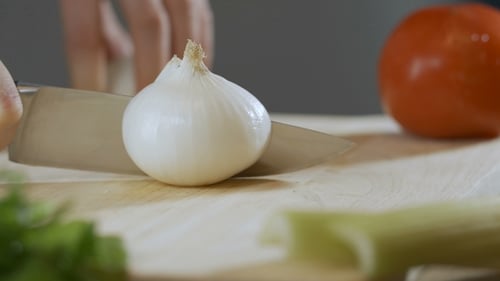 Slicing White Onion on Cutting Board with Knife