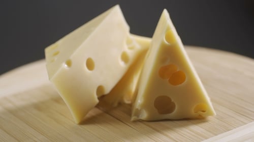 Rotation Delicious Cheese Maasdam on the Cutting Board on Gray Background