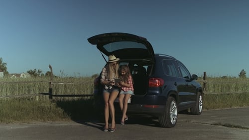 Family Gathers Around Tablet in Car Trunk