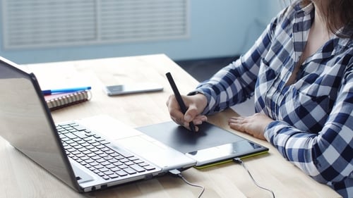 Woman Graphic Designer Working with Digital Drawing Tablet and Pen on a Computer