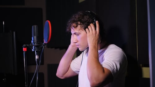 Young Handsome Singer Man Puts on Headphones in the Studio. Recording New Melody or Album
