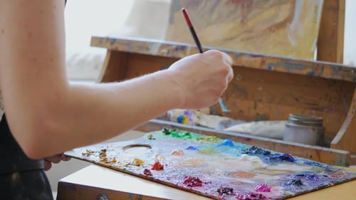 Female Painter at the Studio Creator Makes Piece of Art. The Artist Takes Oil Paint on the Brush