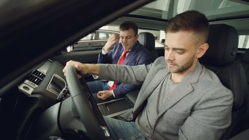 Men Inspect New Car Inside Car Dealership