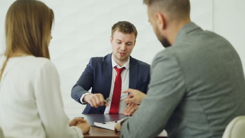 Cheerful Car Dealership Employee Is Shaking Hands with Young Buyer Handsome Man After Signing