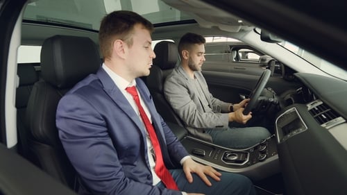 Side View of Two Men Customer and Salesman Sitting in Beautiful Car on Front Seats and Talking