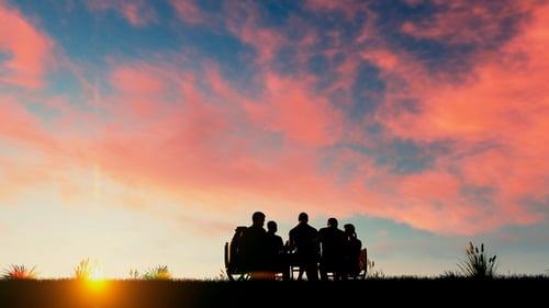 People Silhouettes Sitting on a Bench at Sunset