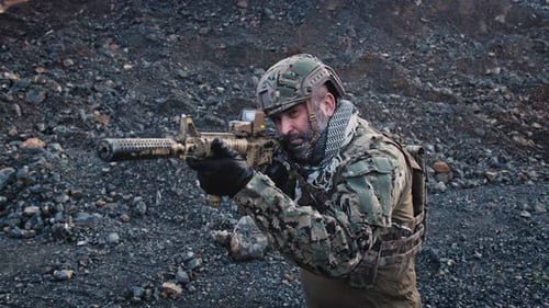 Soldier Aims Rifle in a Rocky Wilderness