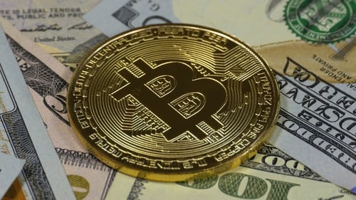 Close Up of Gold Bitcoin on Dollar Bills