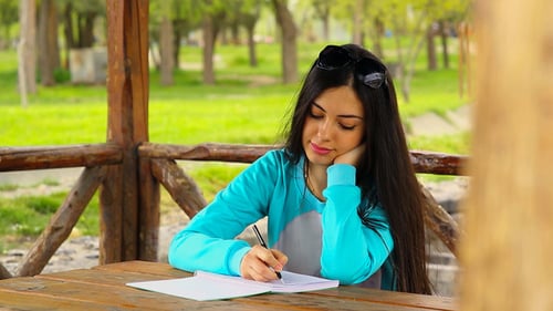 Woman Writing in Notebook at Park Gazebo
