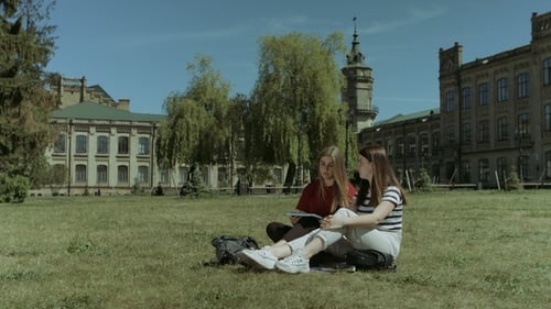 Glückliche Studentinnen entspannen sich auf dem Campus Rasen