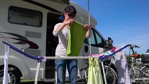 Woman Hanging Laundry to Dry Beside Camper Van