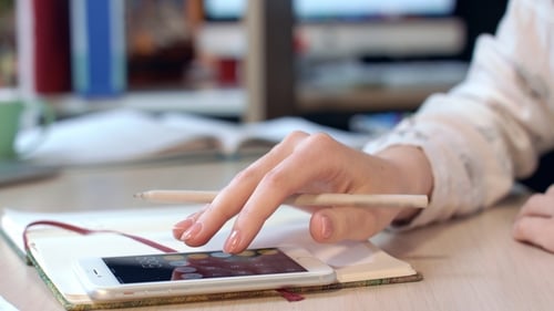 Mano femenina con teléfono móvil para calcular ganancias en el lugar de trabajo de oficina