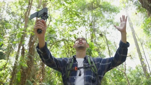 Asian handsome male backpacker vlogger traveling in the forest alone.