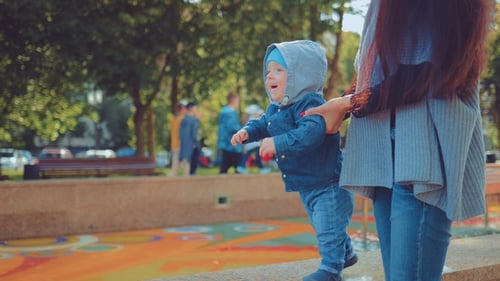Baby First Steps, Mom Supports Her Baby for a Walk in the Park