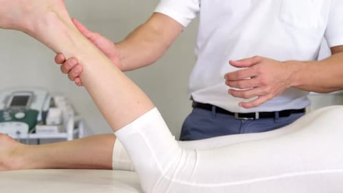 Männlicher Physiotherapeut bei Beinmassage an Patientin