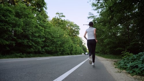 Woman Runner Running on Open Road in Countryside