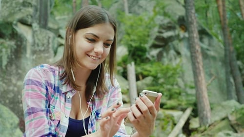 Smiling Woman Using Smartphone in Natural Forest Setting
