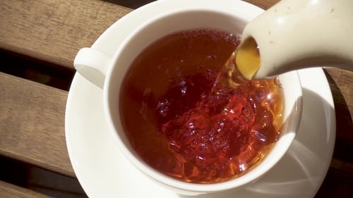 Pouring Hot Dark Tea into a Cup