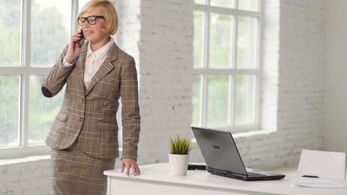 Business Woman Talking on Phone Sitting on Desk