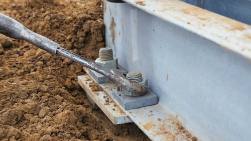 Worker Twists Screw on Metal Tower Support on Ground