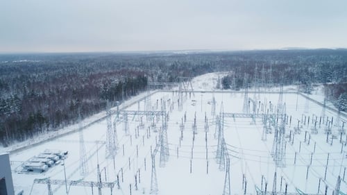 Umspannwerk verteilt Strom gegen mit Schnee bedeckte Bäume