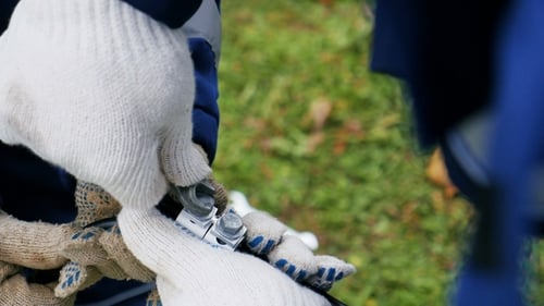 Worker Holds Cable and Colleague Rotates Tool Fixing Fasteners