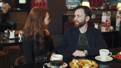 Couple on a Date in a Restaurant. Young Guy and Girl Have Fun Talking While Sitting at a Table