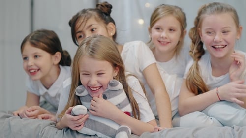 Five Smiling Girls Lying Together on Bed