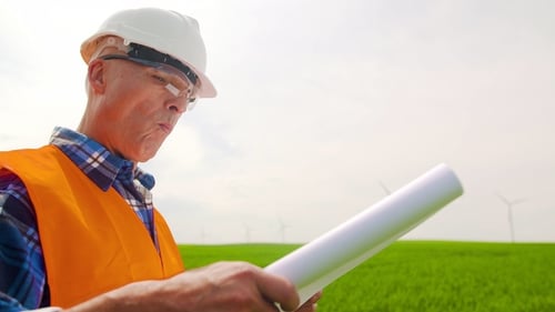 Engineer Analyzing Plan While Standing In Windmill Farm
