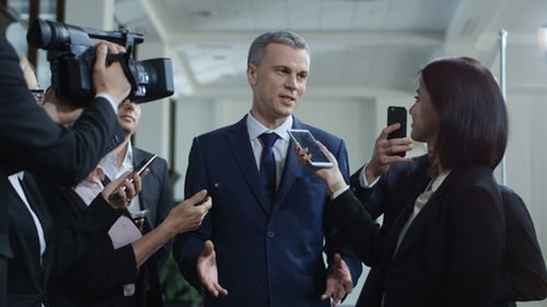 Man Giving a Press Conference Surrounded by Media