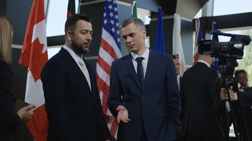 Men in Suits Talking near International Flags