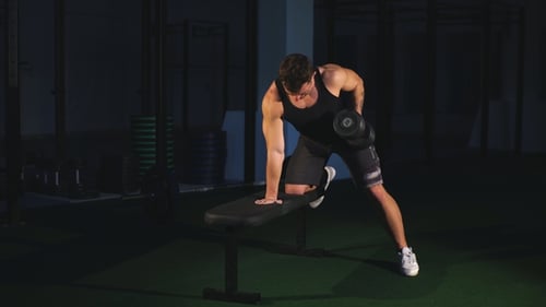 Muscular Bodybuilder Guy Doing Exercises Standing Select with Weight Lifting Dumbbells in Gym