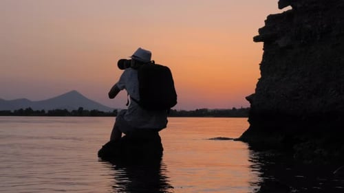 Young Male Photographer Taking Photo During Sunset. Photographer Travels and Takes Pictures